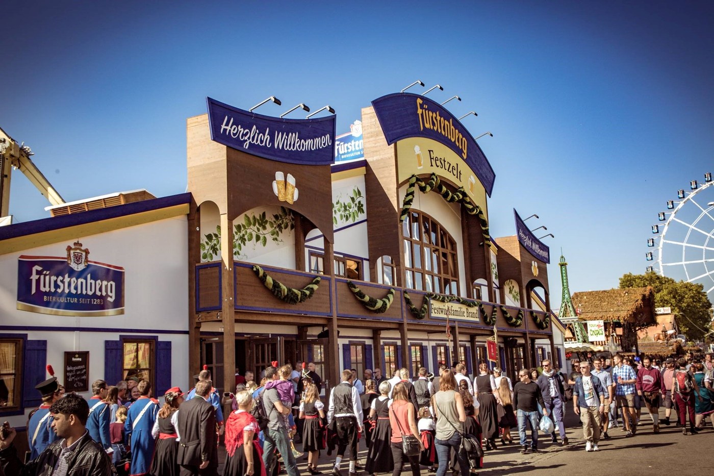 Exterior da tenda Fürstenberg no Cannstatter Wasen, com visitantes em traje tradicional