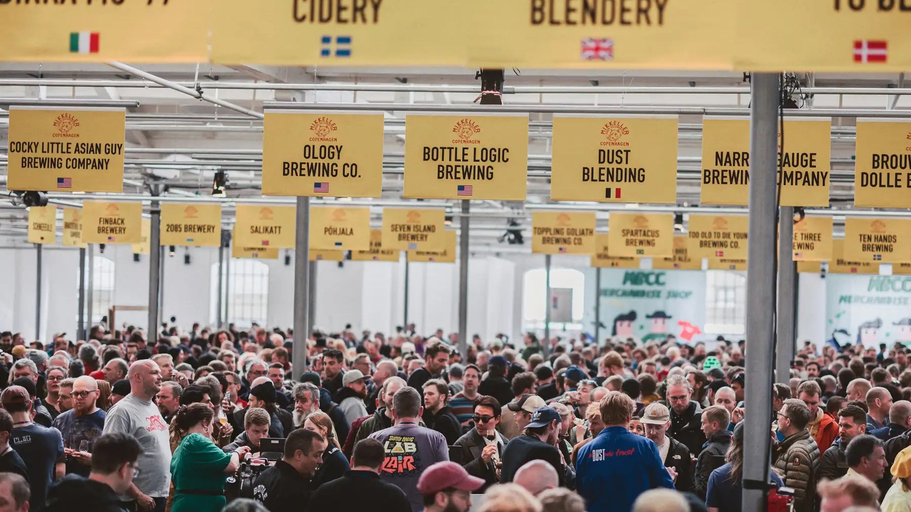 Público no Øksnehallen durante o Mikkeller Beer Celebration Copenhagen, com a sinalética das cervejeiras