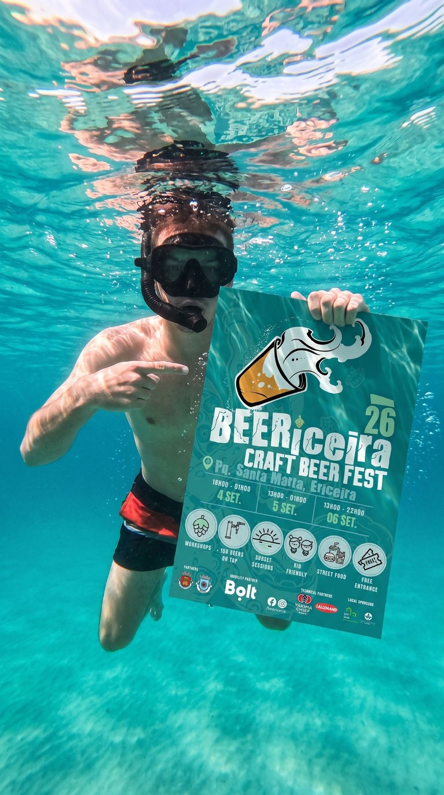 Mergulhador segura o cartaz do BEERiceira 2026 debaixo de água